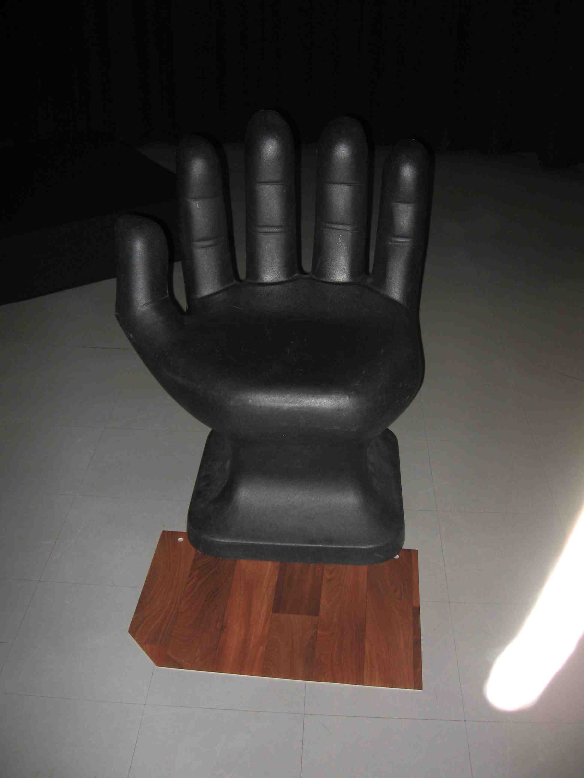 hand-shaped chair with black platform and vinyl wood floor, number 2 vertical